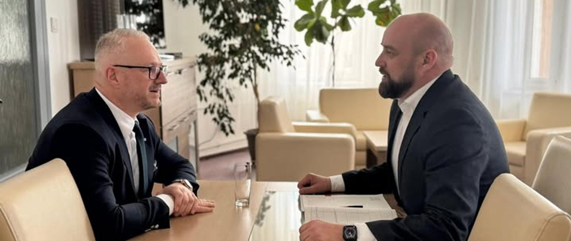 2 mężczyzn w garniturach, w tym wojewoda, siedzą na przeciwko siebie, rozmawiają