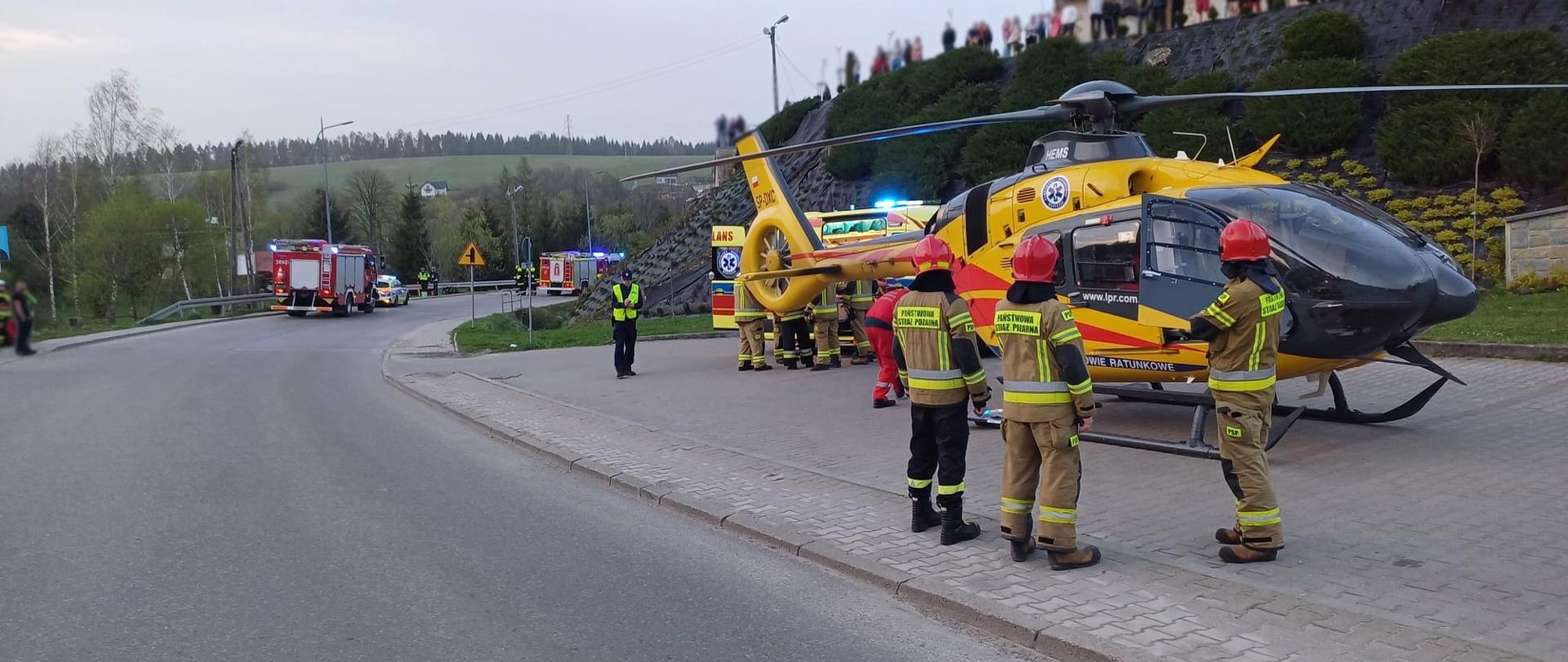 Śmigłowiec na parkingu przed kościołem a obok stoją strażacy