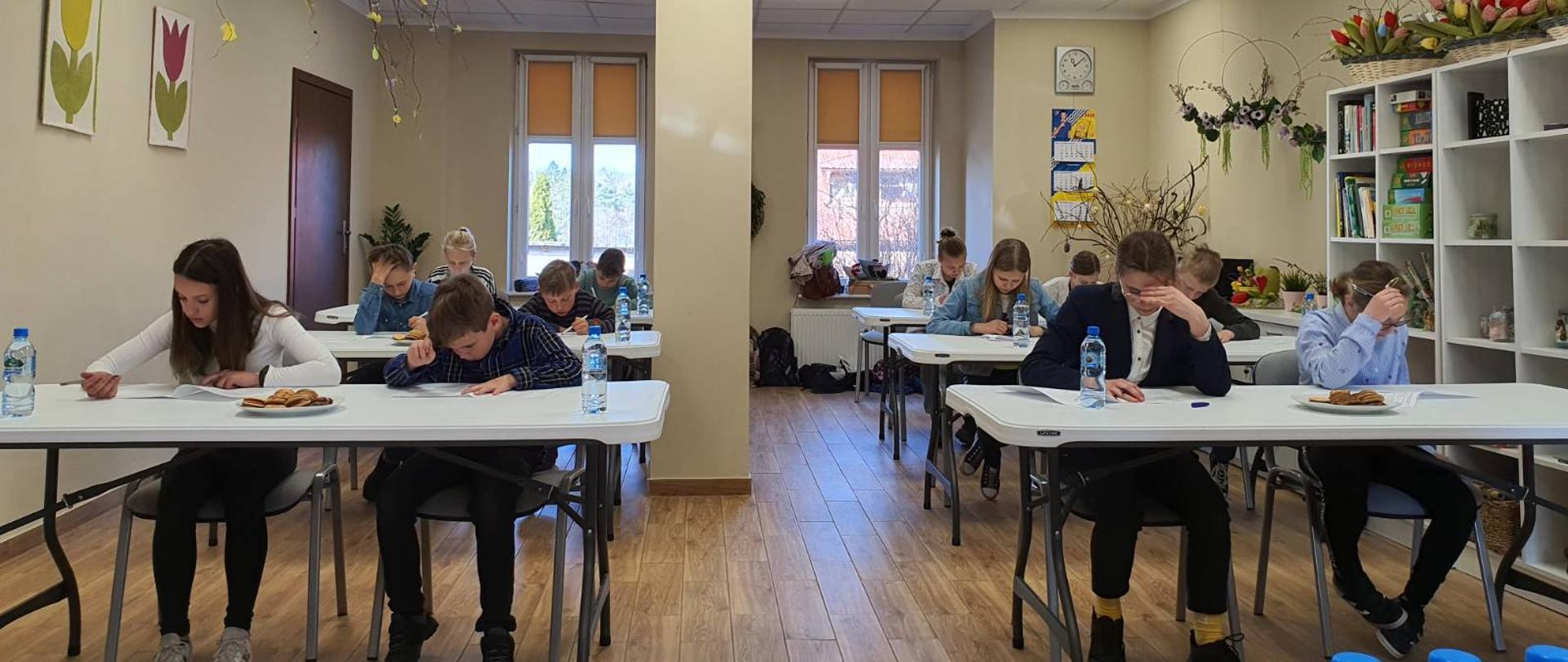 W klasie grupa dzieci zajęta rozwiązywaniem testów wiedzy pożarniczej