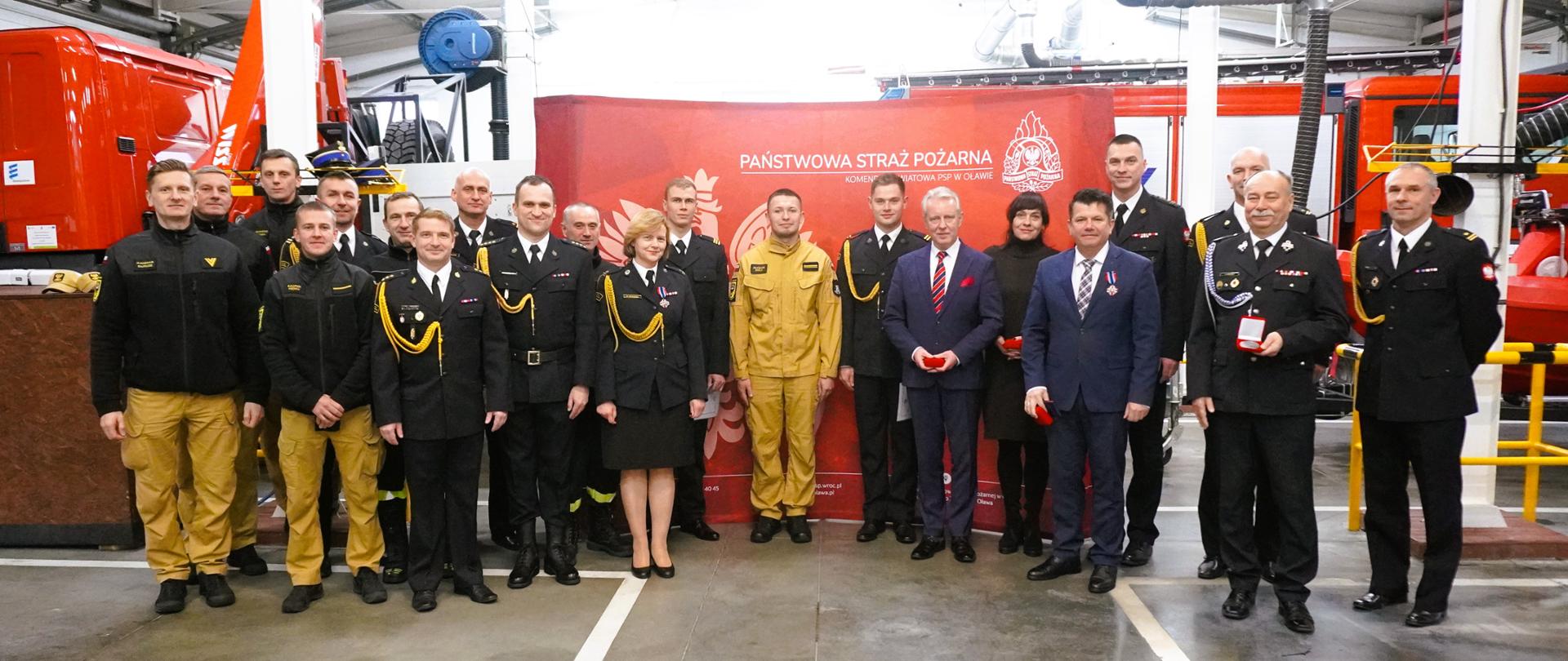 Pamiątkowe zdjęcie uczestników zbiórki na tle wozów strażackich