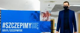 Premier idzie na tle napisu #SzczepimySię.