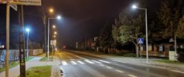 Przejście dla pieszych na drodze jednojezdniowej w terenie zabudowanym, nocą. Widoczne doświetlenie wybudowane specjalnie dla poprawienia widoczności pieszego w obrębie przejścia.