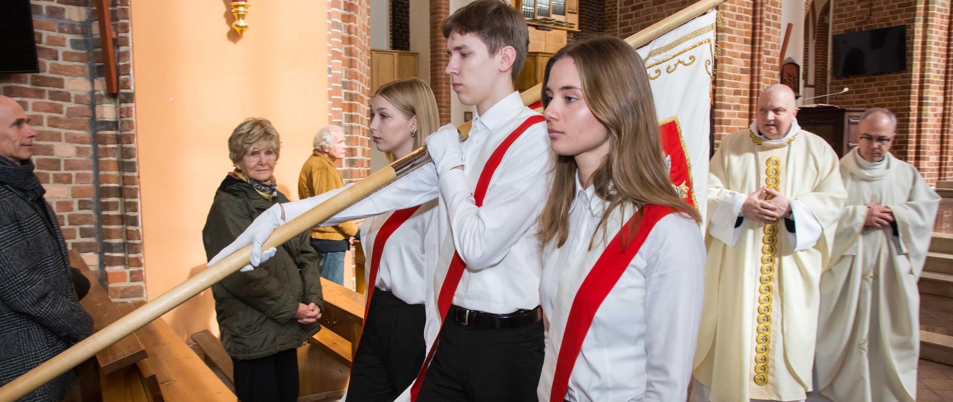 zdjęcie przedstawia poczet sztandarowy odchodzący od ołtarza nawą główną katedry