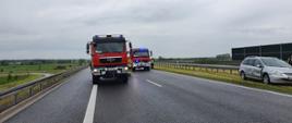 Droga ekspresowa S5. Na jezdni dwa wozy straży pożarnej. Obok nich policjant i strażak. Na pasie zieleni stoi auto osobowe uczestniczące w kolizji.