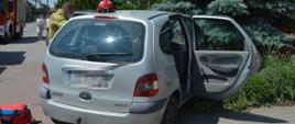 Masłowo, ulica Matejki. Samochód osobowy uderzył w ogrodzenie posesji. Na pierwszym planie renault scenic, koloru srebrnego widziany od tyłu. Z lewej strony strażak rozmawiający z siedzącą wewnątrz kobietą - uczestniczka kolizji. Samochód ma otwarte drzwi . Na dachu leży czerwony hełm. 