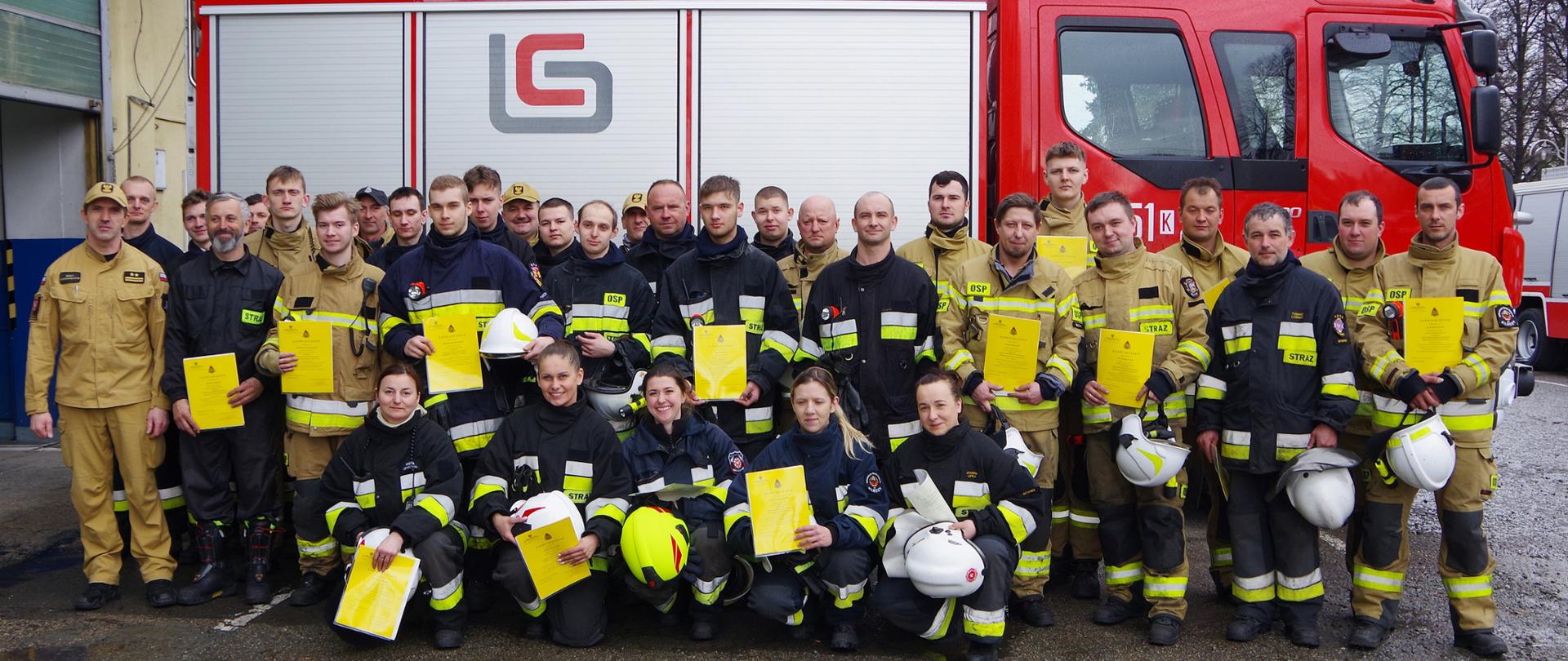 Zdjęcie zbiorowe – uczestnicy szkolenia OSP na tle samochodu pożarniczego.