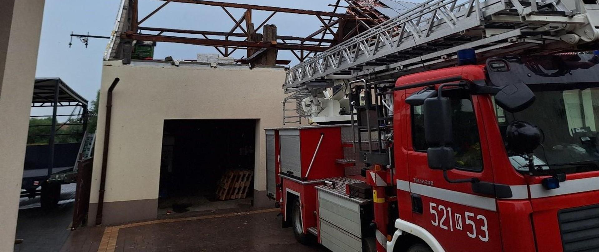 Samochód strażacki na tle zerwanego dachu