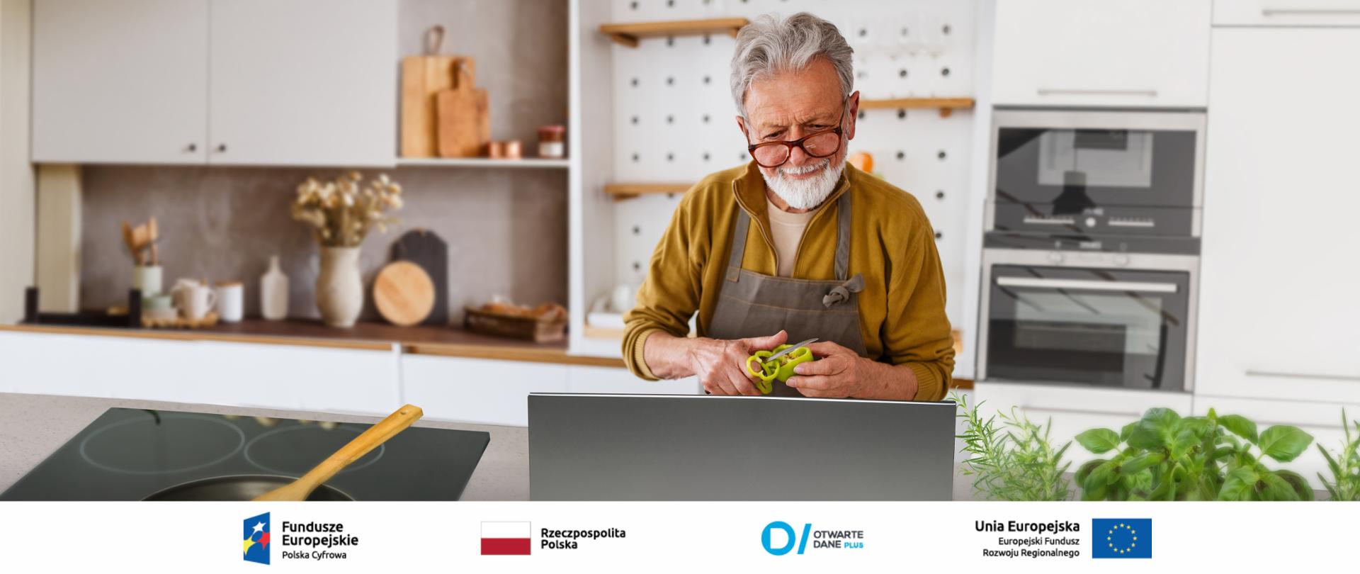 Starszy mężczyzna w kuchni - ubrany w fartuch, kroi paprykę, przed nim stoi laptop (najprawdopodobniej z przepisem na przygotowywaną potrawę).