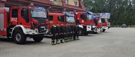 Strażacy na tle pojazdów i garażu uczcili przez sygnały świetlne pamięć powstania warszawskiego