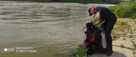Na zdjęciu dwóch strażaków-nurków podczas sprawdzania sprzętu na brzegu rzeki San 
