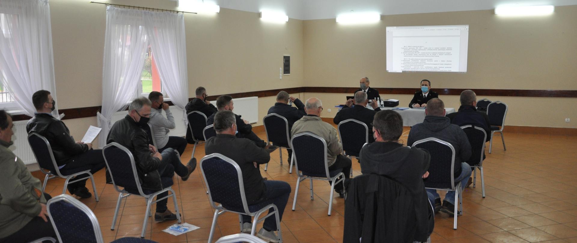 Konsultacje dotyczące ustawy o OSP w powiecie leżajskim. Na zdjęciu widzimy strażaków siedzących przy stole - rozmawiają.