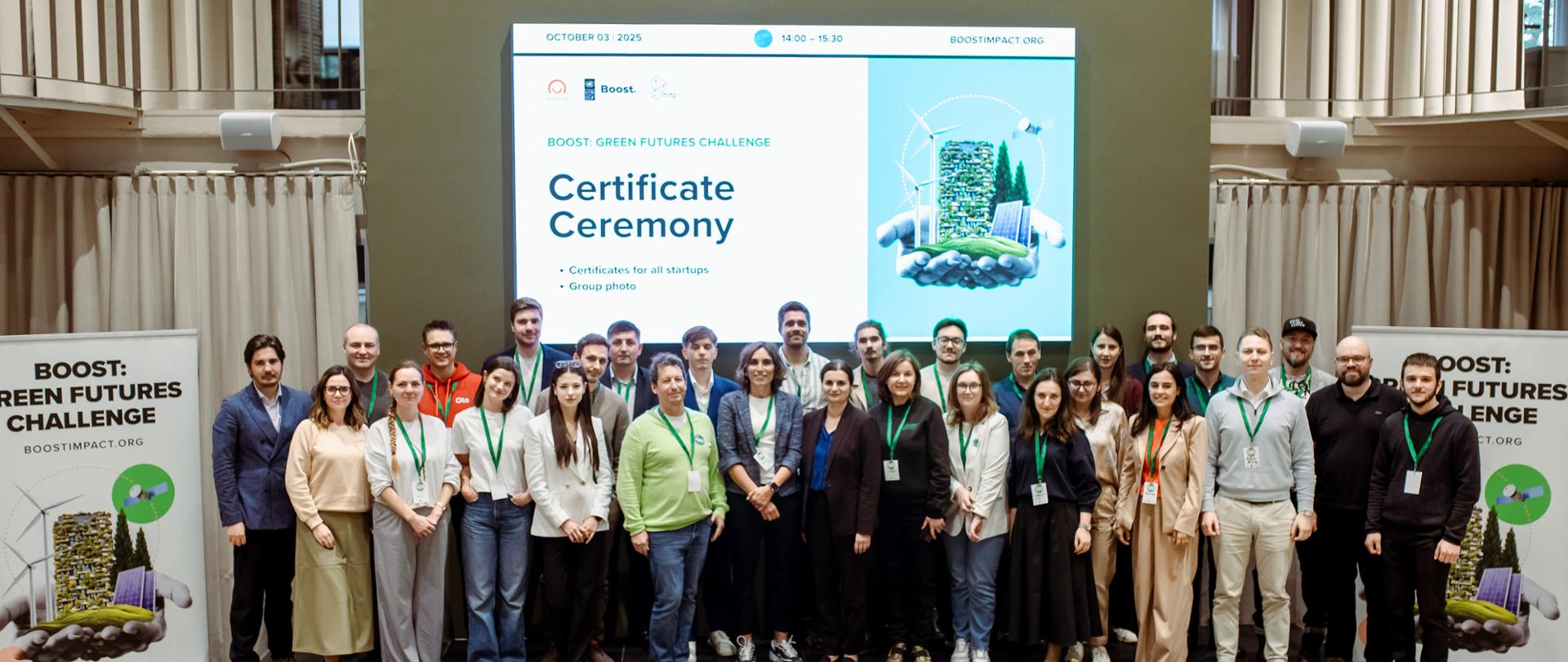 Zbiorcza fotografia uczestników Demo Days w Kiszynowie zrobiona na podeście, z przodu widać kilka wolnych krzeseł a z tyłu banery m.in. z logo Polska pomoc