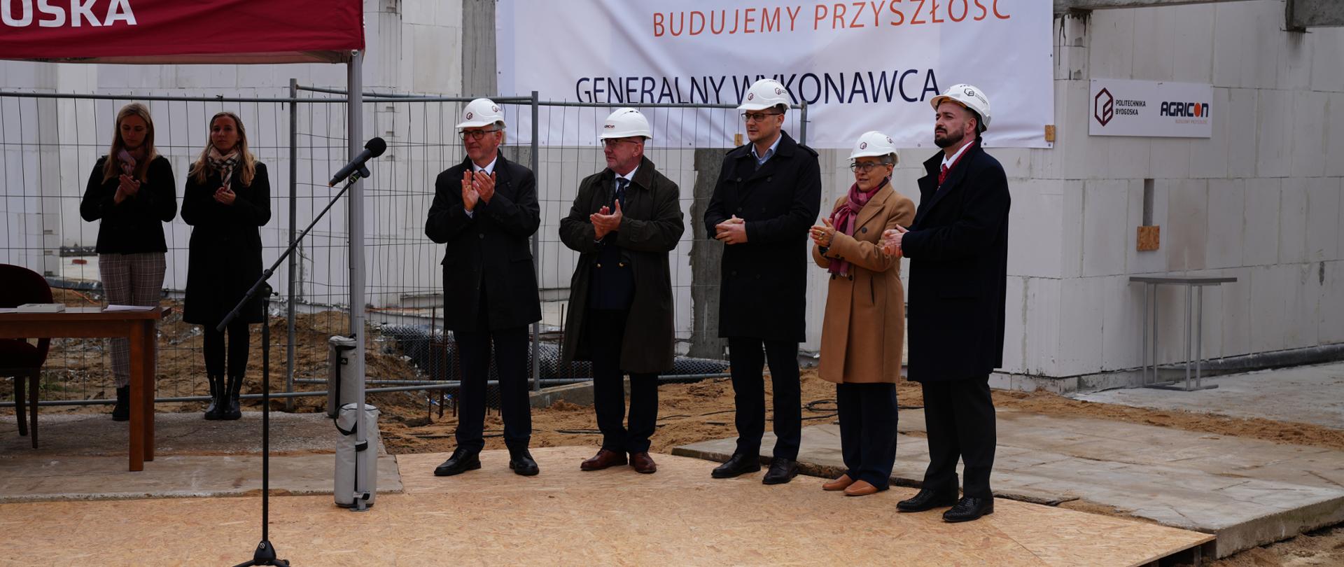 Goście uroczystości na tle murów budynku
