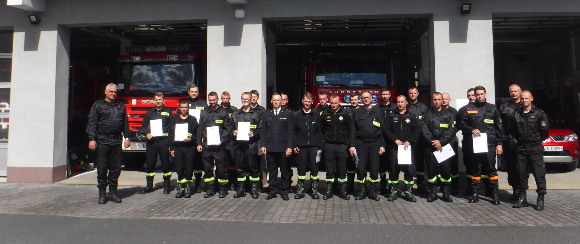 Na zdjęciu widzimy druhów OSP oraz strażaków prowadzących kurs pozujących do grupowego zdjęcia na tle budynku Komendy Powiatowej Państwowej Straży Pożarnej w Leżajsku.