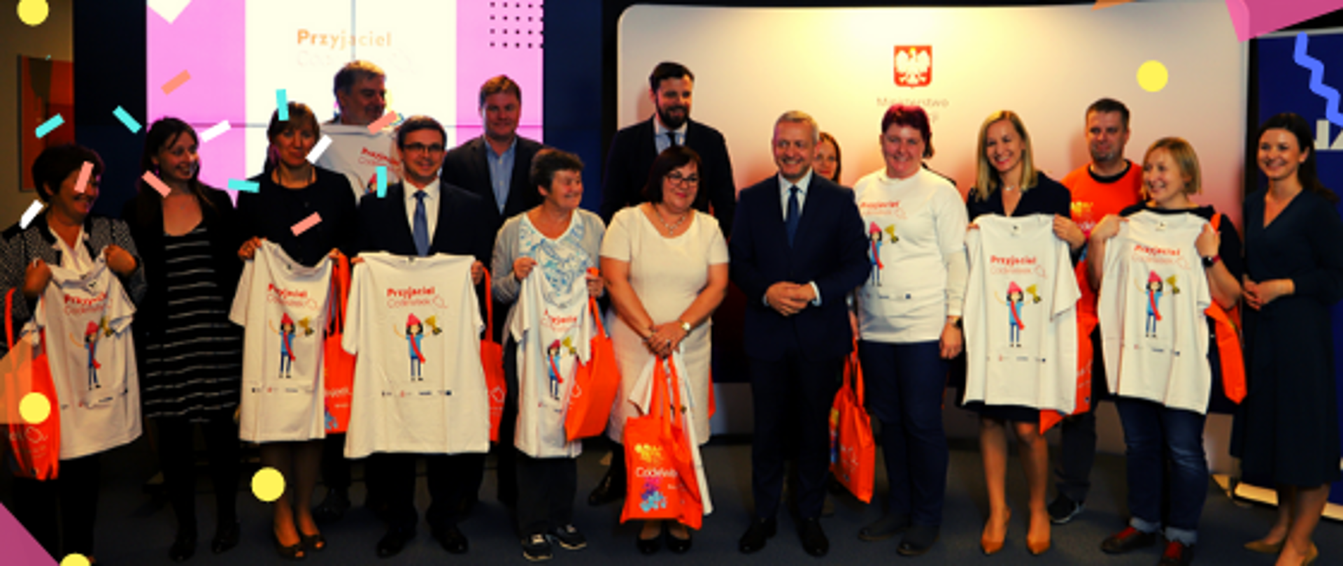 Zdjęcie przedstawia kilkanaście dorosłych osób pozujących i prezentujących koszulki "Przyjaciel Codeweek". U dołu znajduje się pasek logotypów: Europejskie Fundusze Polska Cyfrowa, Ministerstwo Cyfryzacji, NASK i Unia Europejska Europejski Fundusz Rozwoju Regionalnego.