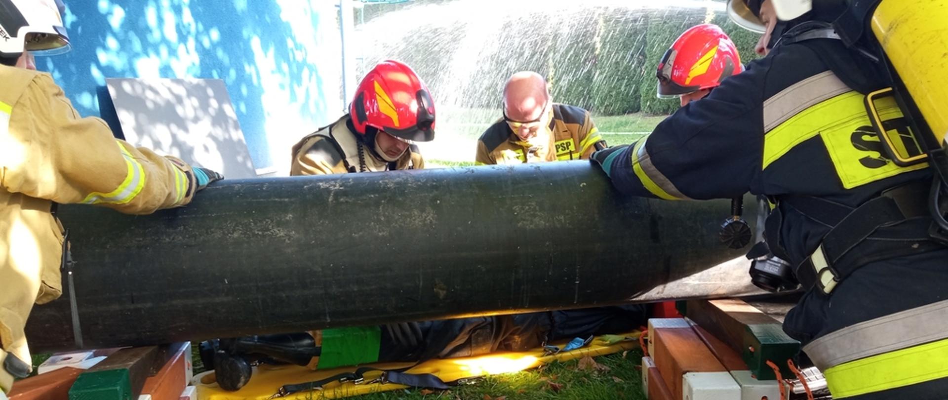 Na zdjęciu strażacy podczas ćwiczeń taktyczno-bojowych pk „Skażenie 2022" wydobywający przy użyciu poduszek powietrznych wysokociśnieniowych spod zawaliska ranną osobę.