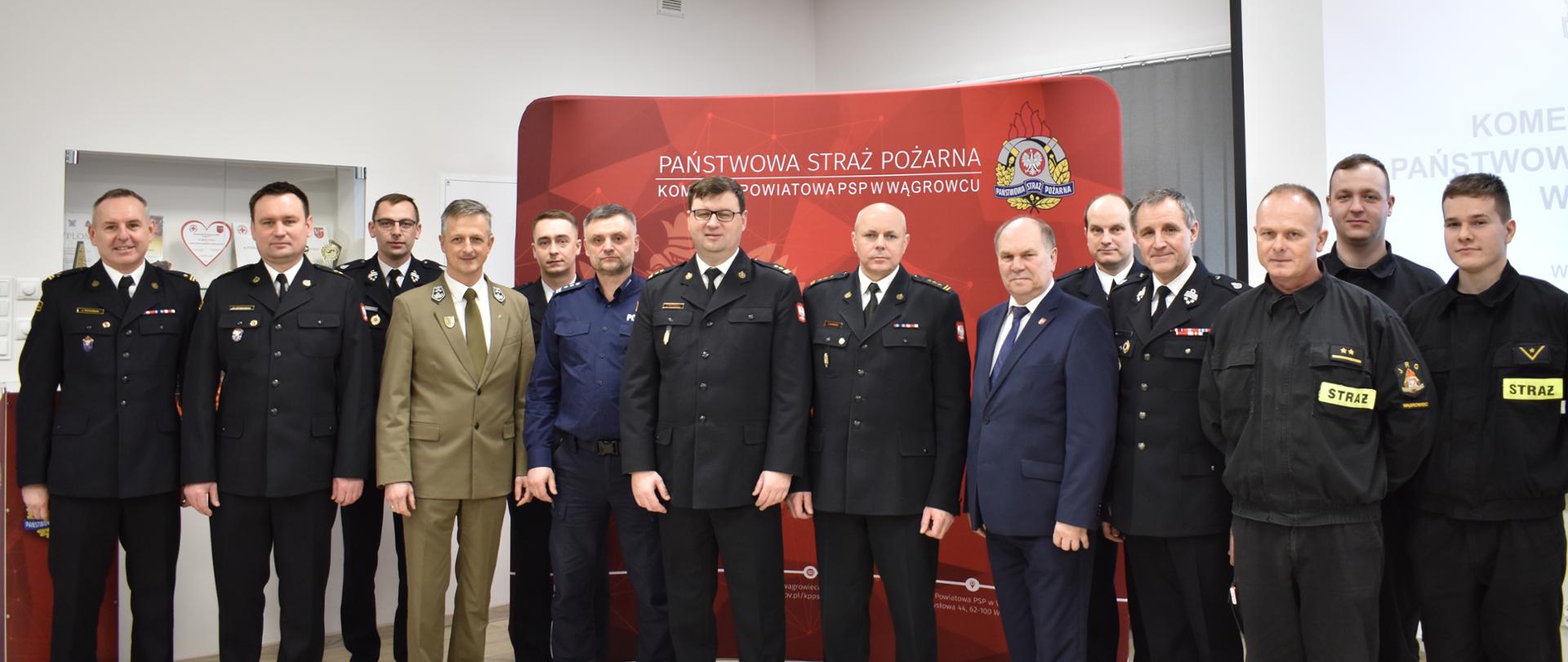 zdjęcie grupowe strażaków , policjantów , nadleśniczych, w tle czerwony baner