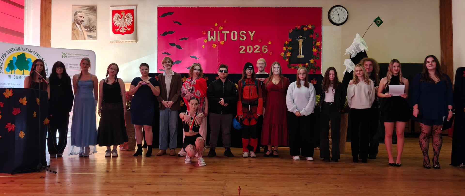 Grupa uczniów i nauczycieli pozuje na scenie auli pod napisem Witosy 2026.