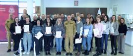 Pamiątkowe zdjęcie grupowe uczestników szkolenia inspektorów ochrony przeciwpożarowej (26 osób) w towarzystwie Zastępcy Komendanta Centralnej Szkoły PSP, kobiety oraz dwóch funkcjonariuszy CS PSP
