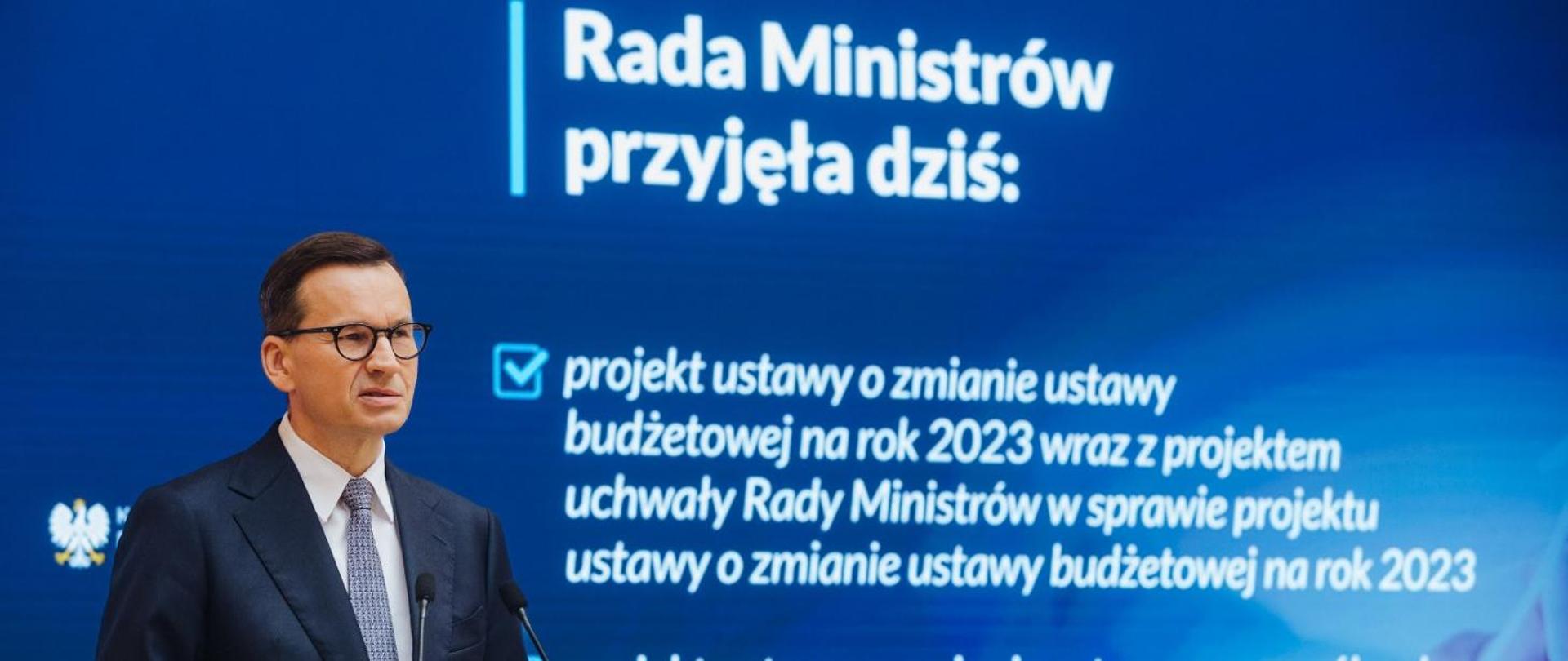 premier Mateusz Morawiecki na niebieskim tle z białymi napisami 