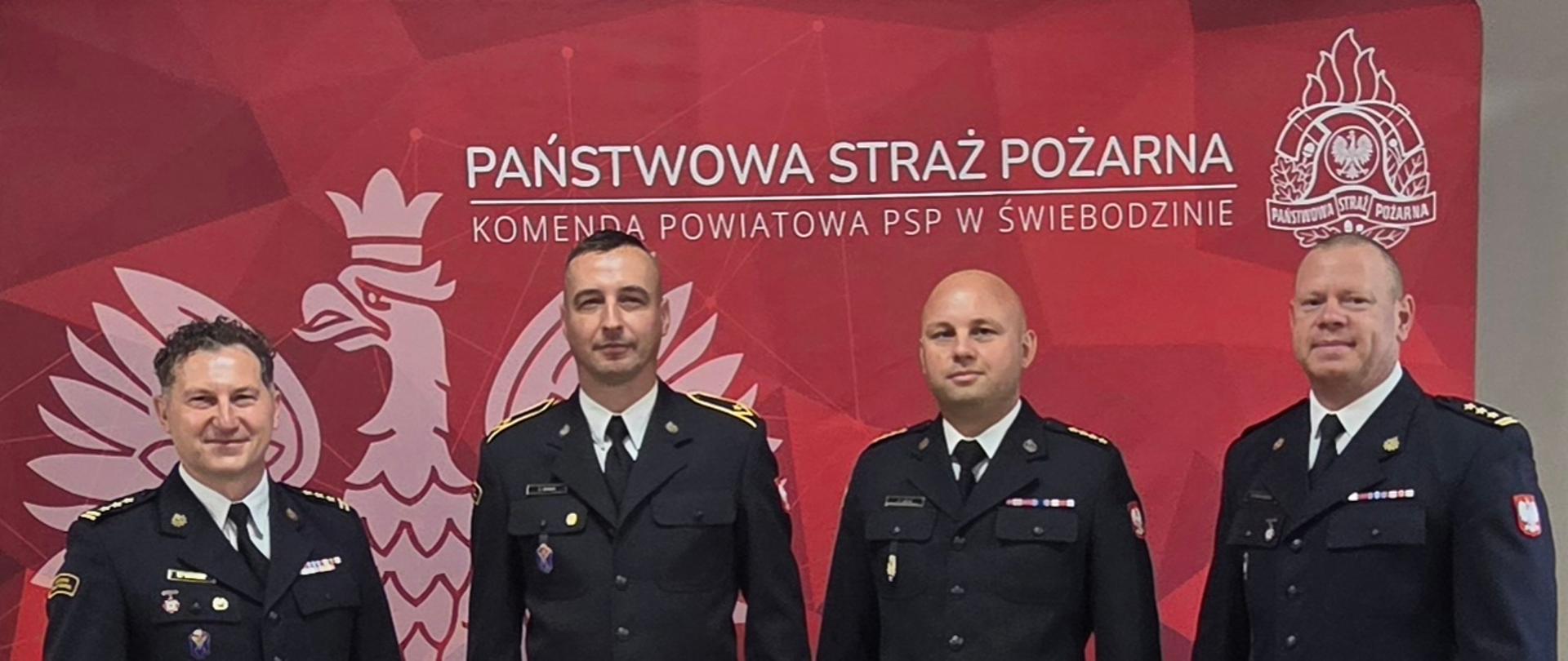 Zdjęcie okolicznościowe po wręczeniu nagrody pieniężnej dla młodszego aspiranta Grzegorz Grabasa z udziałem Komendanta Powiatowego PSP starszego brygadiera Mariusza Wójcika, Zastępczy Komendanta starszego brygadiera Marcina Bohuszko oraz Zastępcy Dowódcy Jednostki Ratowniczo Gaśniczej starszego kapitana Pawła Lecha