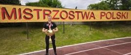 Na zdjeciu widoczny jest kpt. Robert Zdonek trzymający puchar na tle baneru Mistrowstwa Polski, który na co dzień pełni funkcję Zastępcy Dowódcy zmiany.