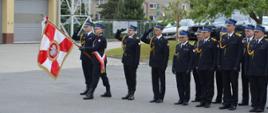 Na zdjęciu widoczny pododdział pożarniczy Komendy Powiatowej Państwowej Straży Pożarnej w Głubczycach w dwuszeregu podczas oddawania honory w związku z odgrywaniem Hymnu Państwowego.