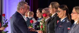W szeregu stoją kobiety w mundurach różnych formacji. Wojewoda wręcza czerwone róże.