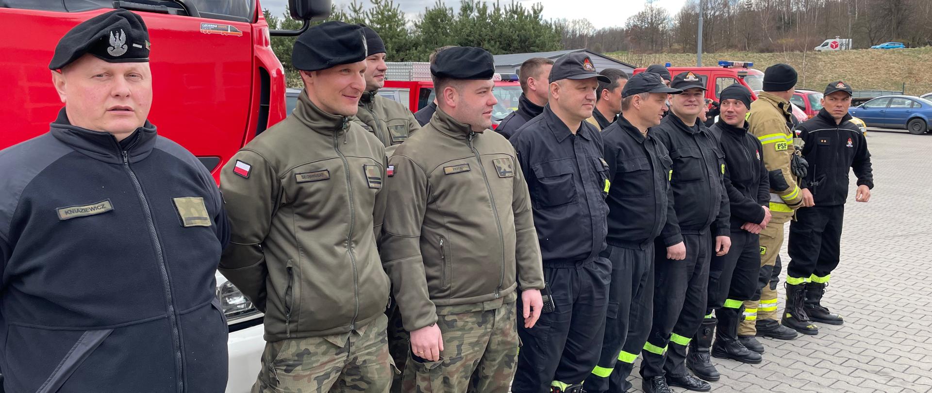 Na zdjęciu widać żołnierzy oraz strażaków podczas rozpoczęcia szkolenia. Funkcjonariusze ubrani w umundurowanie koszarowe. 