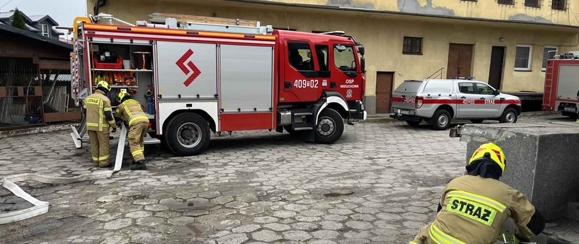 Zdjęcie przedstawia ratowników podczas ćwiczeń przed budynkiem piekarni.