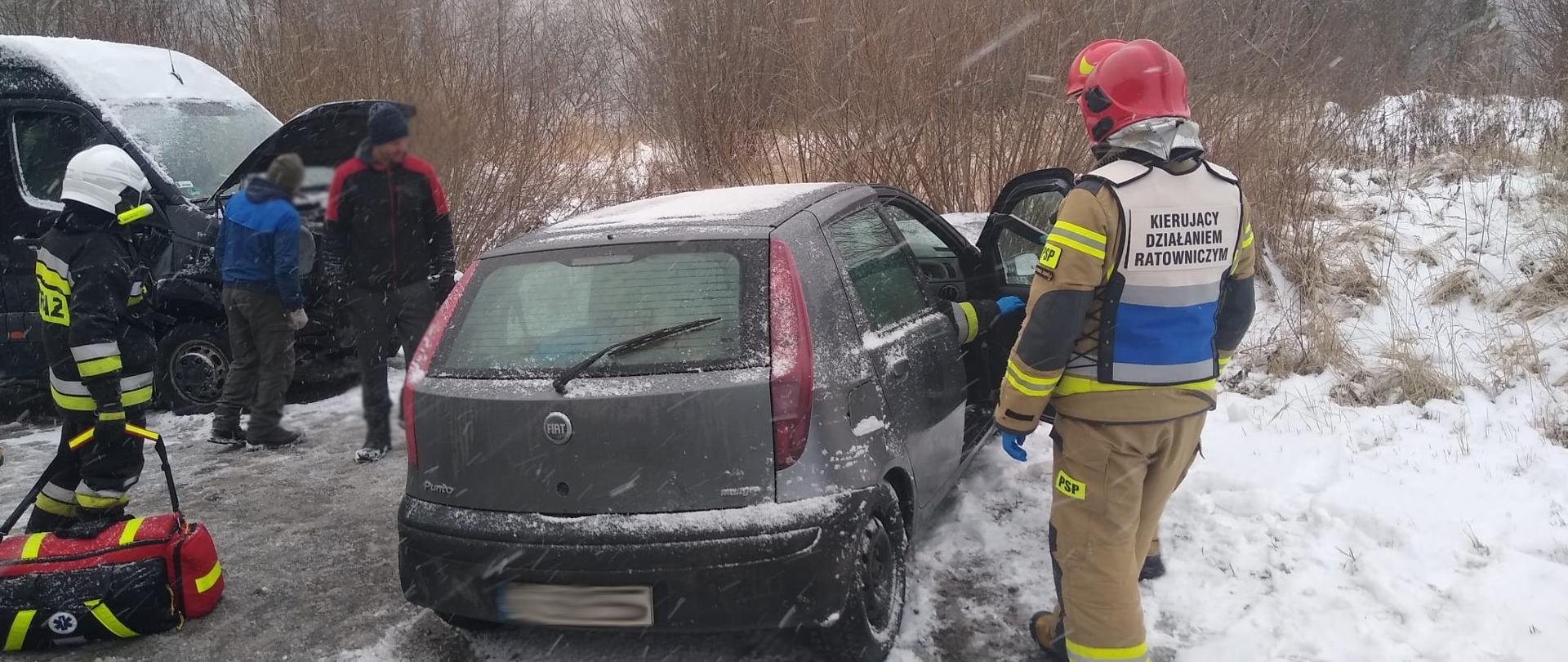 Samochody uczestniczące w zdarzeniu a obok strażacy.