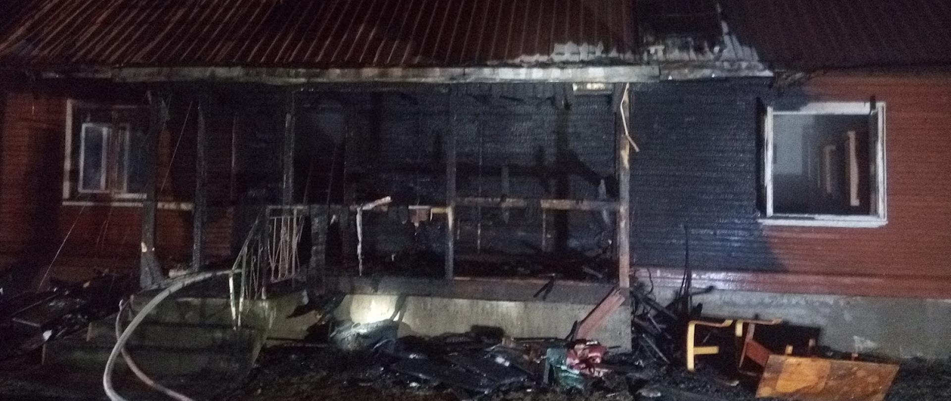 Zdjęcie przedstawia spalona część elewacji domu drewnianego 