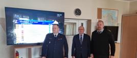 Fotografia przedstawia Komendanta Powiatowego PSP w Malborku, Starostę Powiatu Malborskiego oraz dyżurnego Stanowiska Kierowania Komendanta Powiatowego PSP w Malborku na tle nowo przekazanego telewizora.
