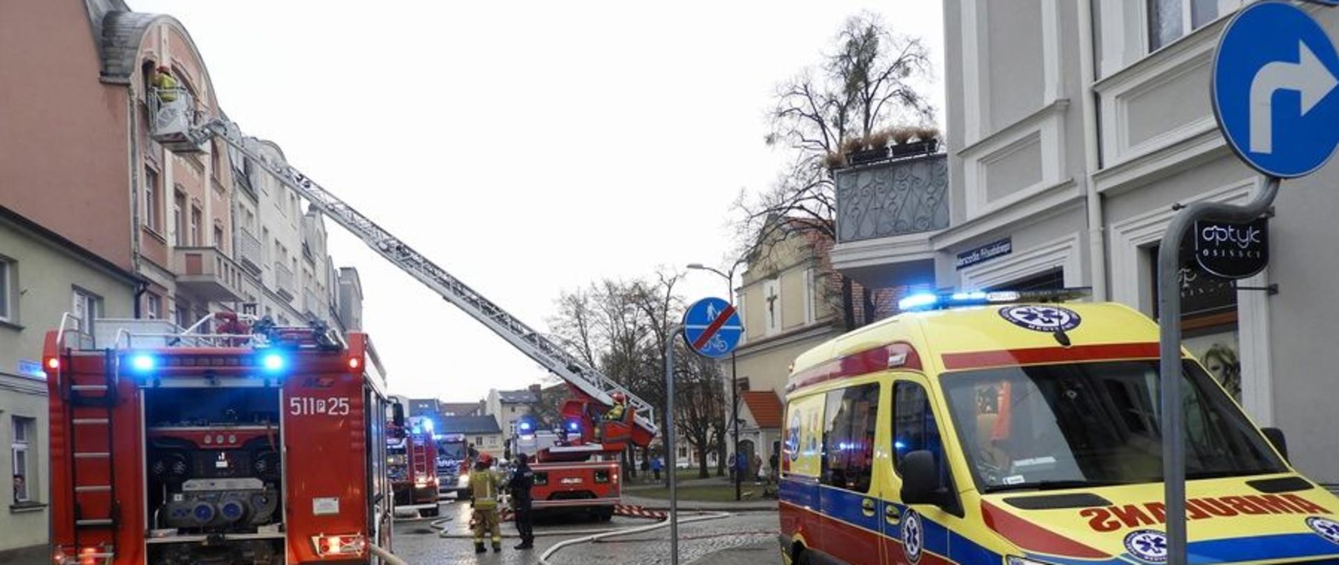 Karetka Zespołu Ratownictwa Medycznego oraz samochody strażackie podczas działań.