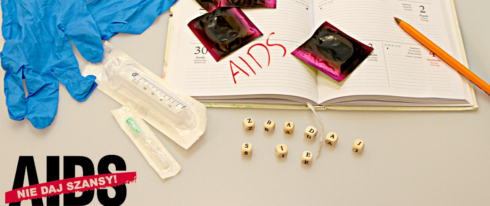 Na jasnym tle leży kalendarz otwarty na 1 grudnia, opakowane prezerwatywy, rękawiczki i strzykawki jednorazowe
