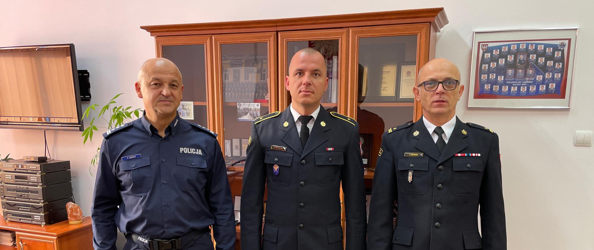 Na zdjęciu Komendant PSP w Śremie, Komendant Powiatowy Policji w Śremie oraz wyróżniony asp. Piotr Michalski który trzyma list gratulacyjny oraz drobny upominek