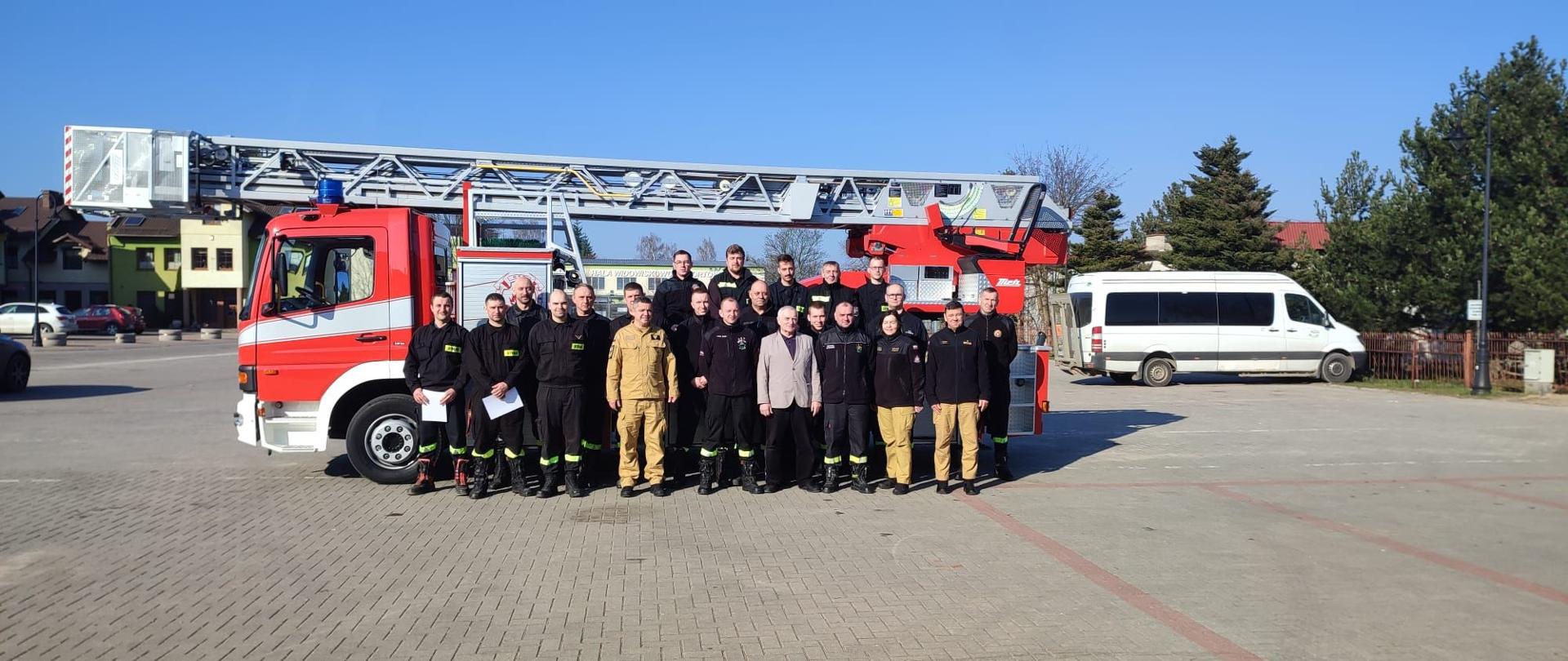 Pamiątkowe zdjęcie uczestników kursu na tle drabiny mechanicznej