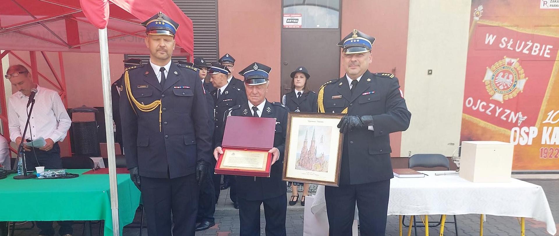 Przedstawiciel Mazowieckiego Komendanta Wojewódzkiego PSP w Warszawie wraz z Komendantem Powiatowym PSP w Makowie Mazowieckim wręcza Prezesowi OSP ryngraf oraz obraz.