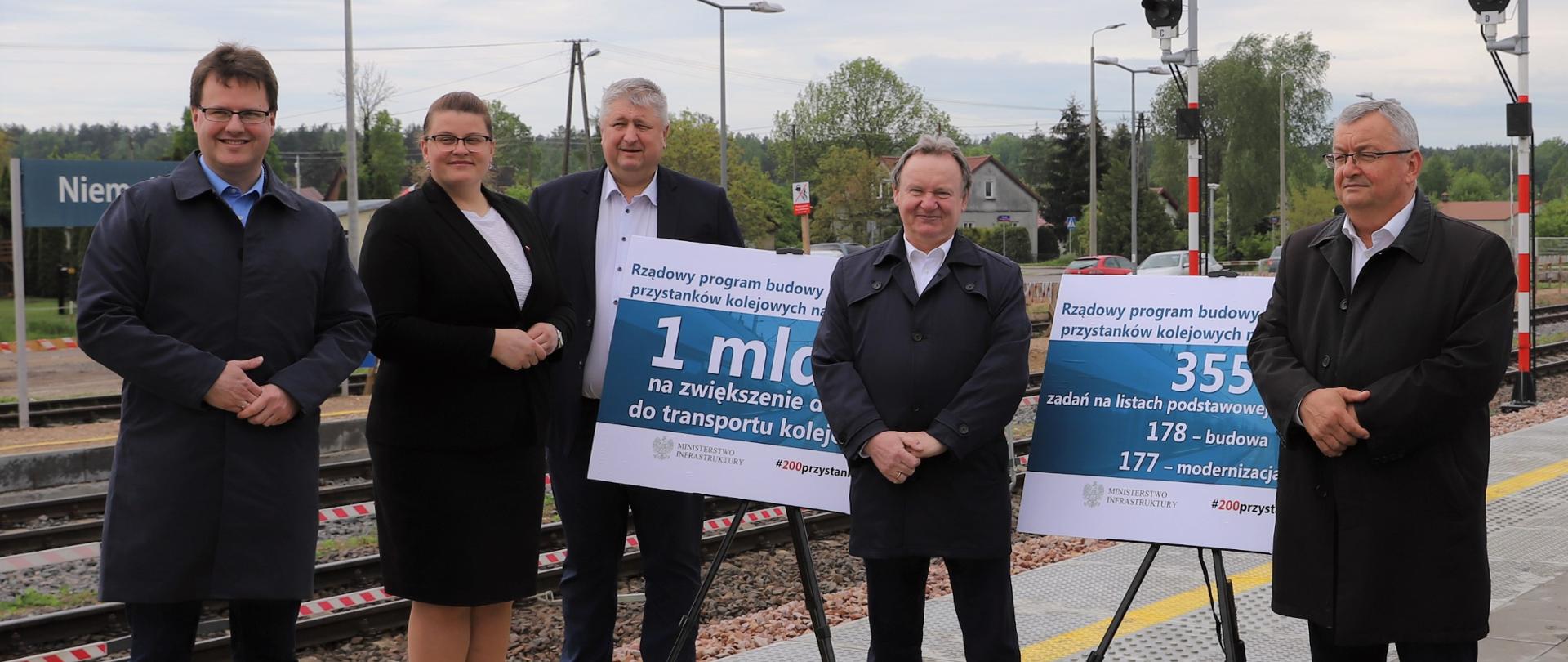 Na zdjęciu znajduje się czterech mężczyzn i kobieta. Osoby te znajdują się na peronie kolejowym. 