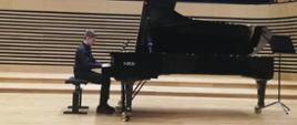 Uczeń gra na fortepianie na scenie sali koncertowej PSM