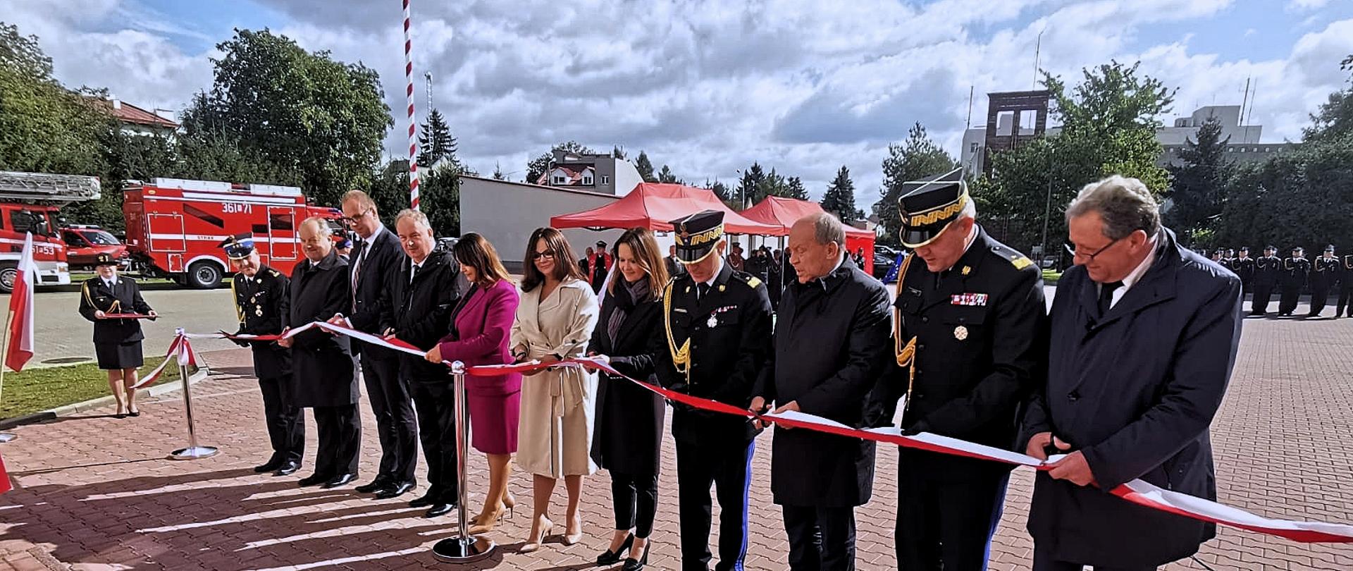 Komendant Główny w asyście innych gości dokonuje symbolicznego przecięcia wstęgi