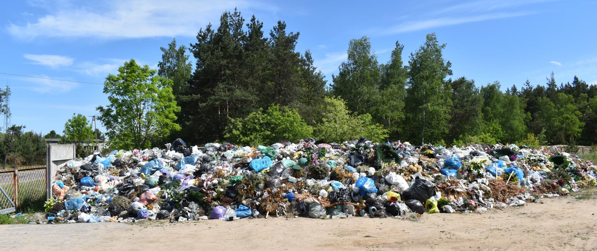 Pryzma z nielegalnie zgromadzonymi odpadami cmentarnymi znajdującą się na otartym terenie.