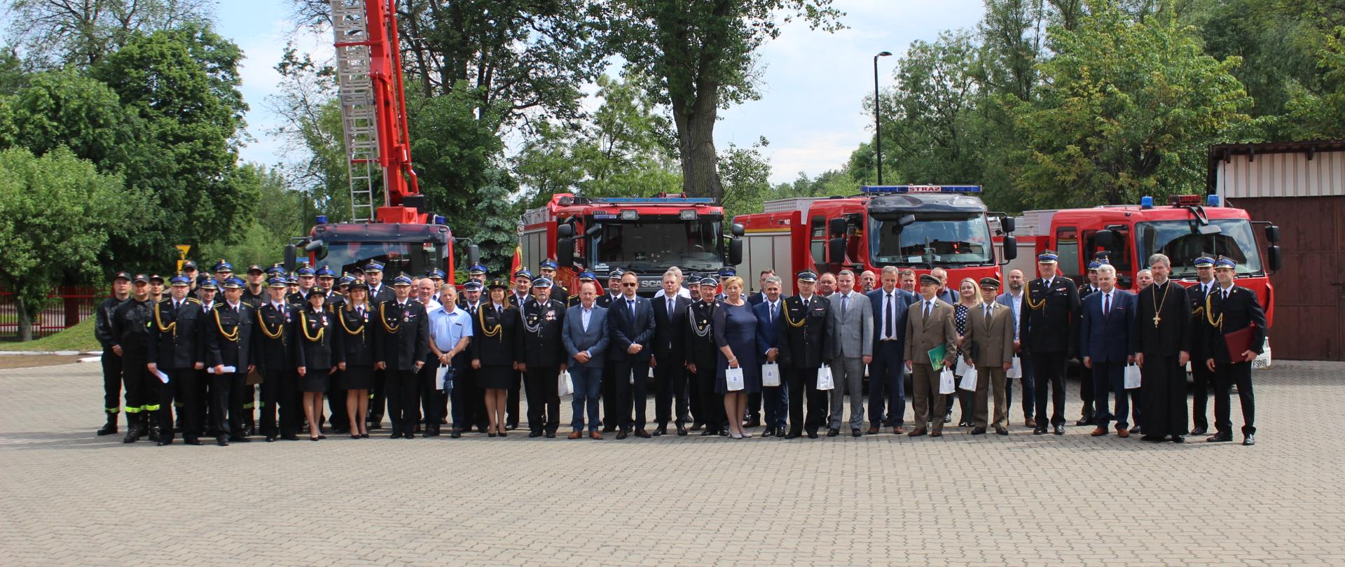 Zdjęcie przedstawia uczestników uroczystości na tle wozów bojowych Państwowej Straży Pożarnej