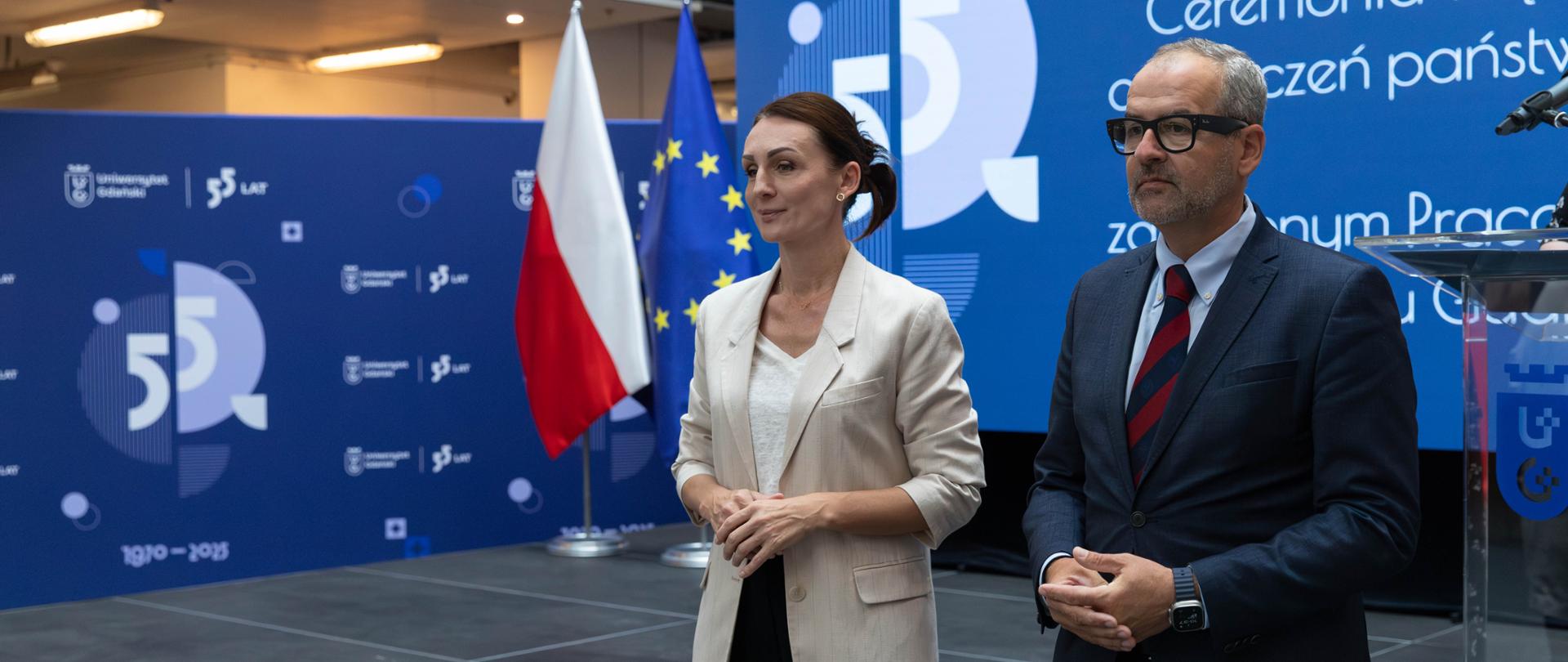 dwie osoby kobieta i mężczyzna stoją przed tablica z napisem 55 lat Uniwersytetu Gdańskiego