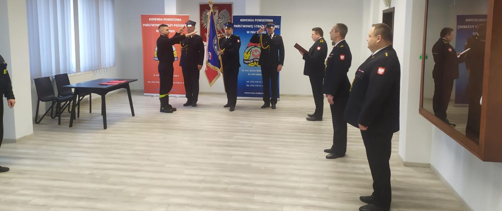 Strażak składający ślubowanie. W tyle poczet sztandarowy.