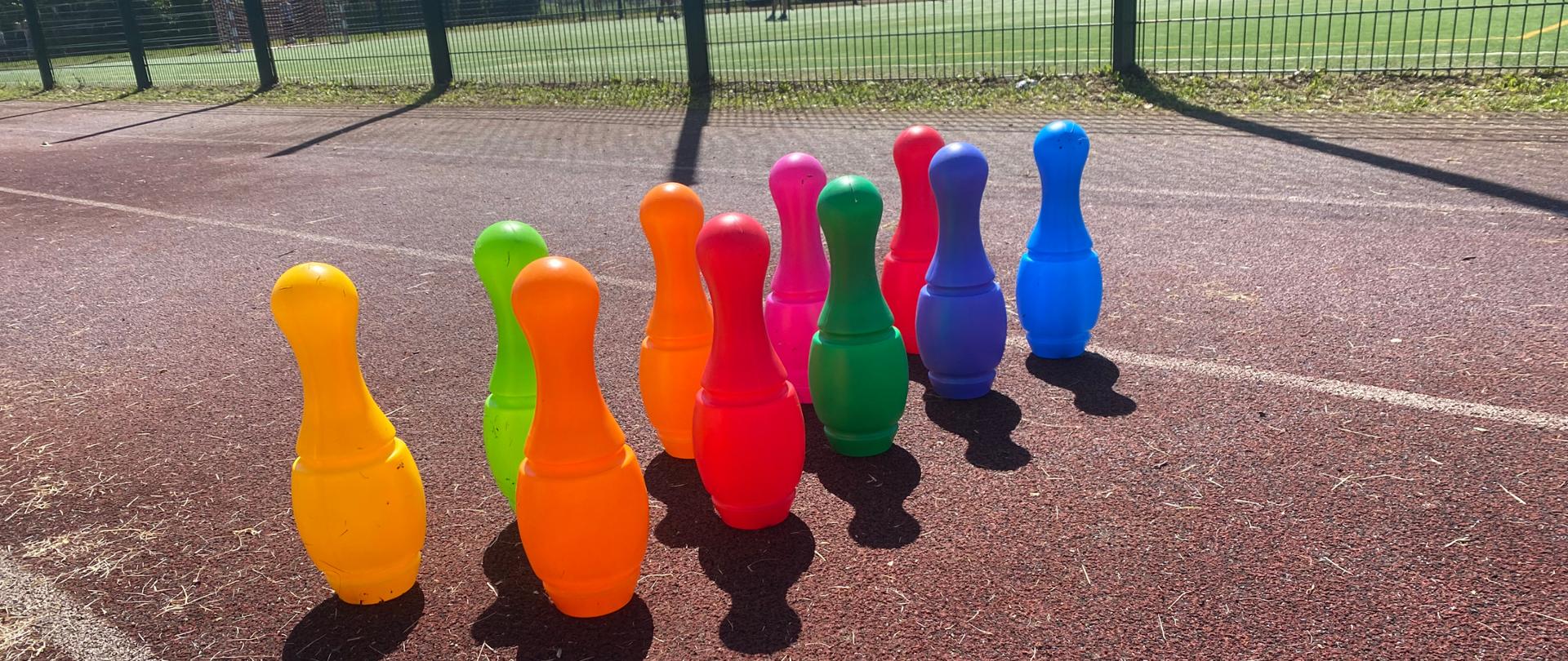 Kolorowe kręgle ustawione na bieżni boiska 