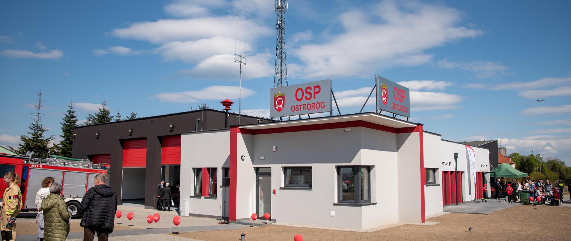 Szaro, grafitowy budynek z banerem "OSP OSTRORÓG"