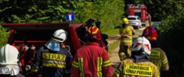 Zdjęcie przedstawia strażaków podczas przemieszczania się samochodem typu Pickup i podawania prądu wody w ruchu