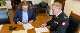 Przy stole po prawej stronie siedzący w umundurowaniu wyjściowym Komendant Miejski a na wprost Prezyden Miasta pan Jacek Karnowski podpisuję porozumienie