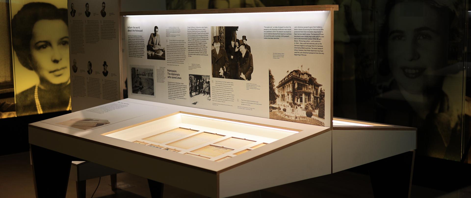 Stół z kopią dokumentów, przedstawiający paszporty, zdjęcia i inne dokumenty wydawane przez Grupę Ładosia